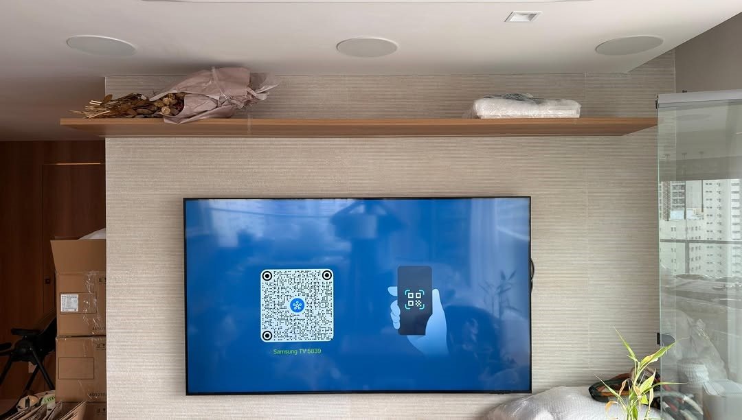 Sala com televisão e sistema de áudio instalados em painel de madeira